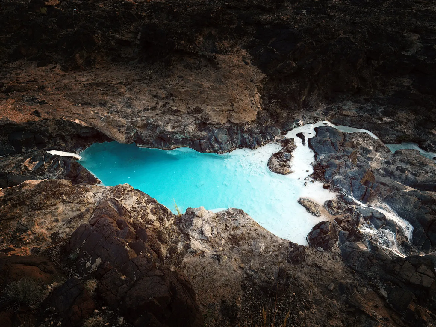 solid white carbonate settled at the bottom of a pool after reacting with volcanic rock formations in Oman, New York Times